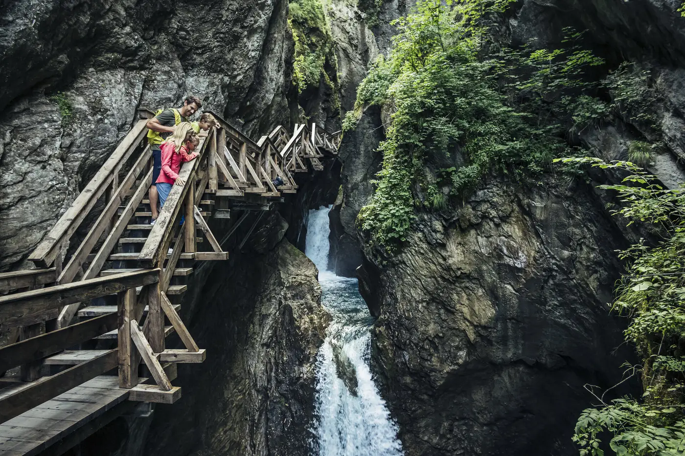 Familie auf dem Holzsteg in der Sigmund-Thun-Klamm zwischen Felswänden und Wasserfällen