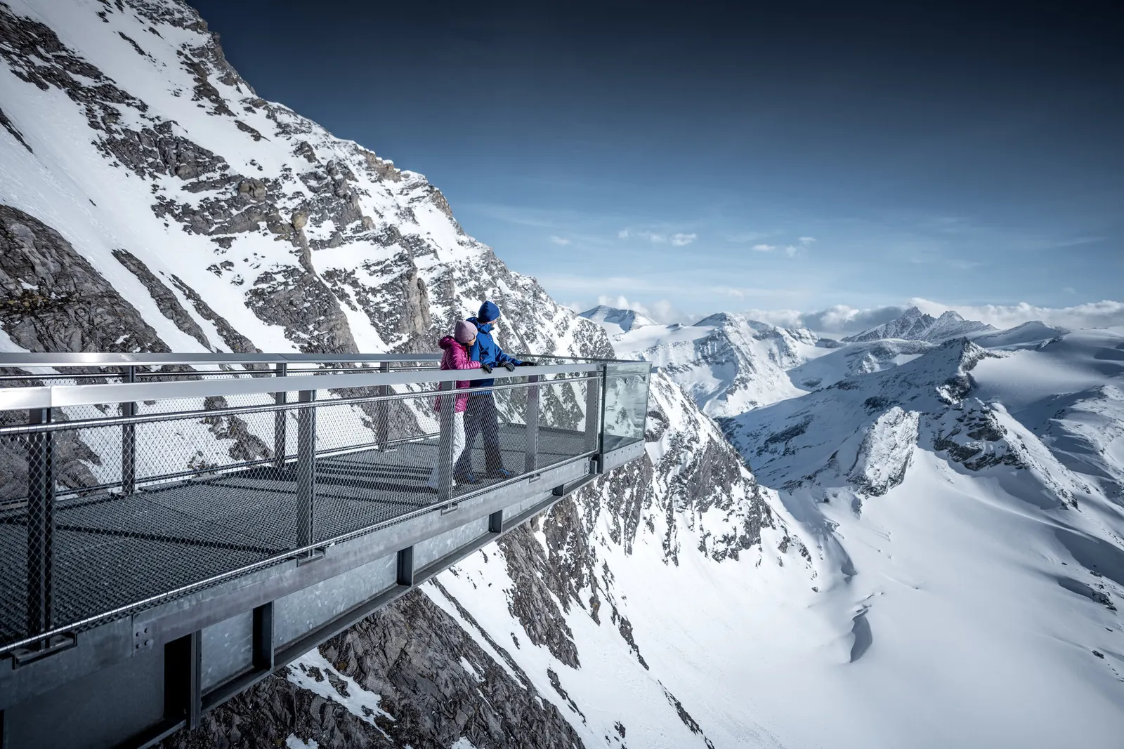 Zwei Personen auf der Aussichtsplattform Top of Salzburg am Kitzsteinhorn mit Blick auf Gletscher und Berge