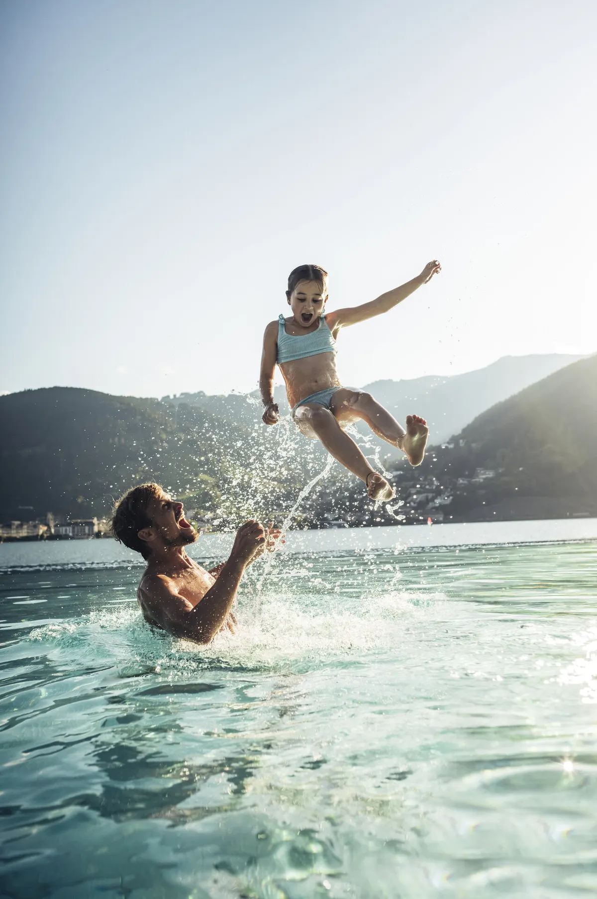 Zwei Badegäste im Wasser des Zeller Sees im Strandbad Thumersbach, im Hintergrund Berge