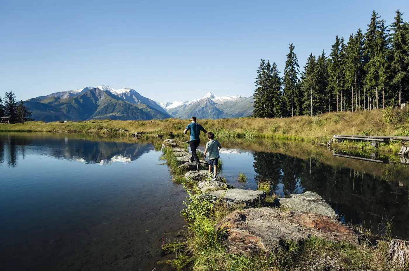Familie wandert an einem Speicherteich mit Bergpanorama in Zell am See-Kaprun